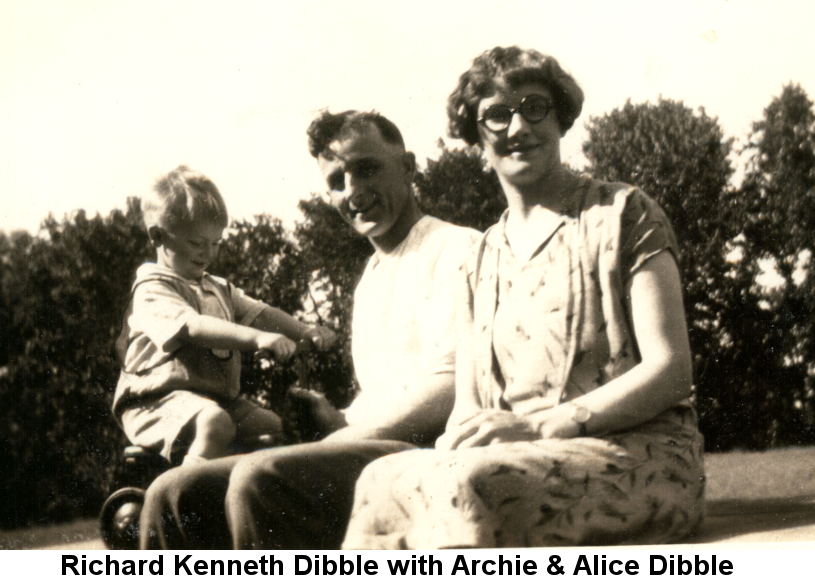 Black and white photo of Richard Kenneth Dibble, about three years old, on a tricycle behind his parents, Archie in a white knit shirt and Alice with bobbed hair, black-framed glasses and a flowered dress, seated on a bench.